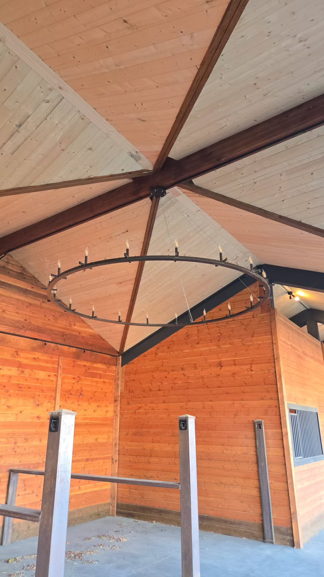 Timber-lined Cavalli stable interior with stall grille, beams and a ring chandelier